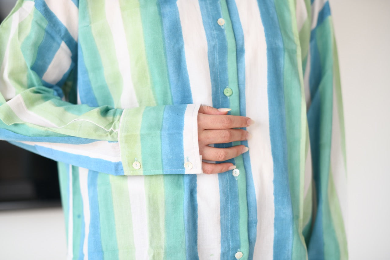 Close-up of a person wearing a aqua striped shirt with a blurred background