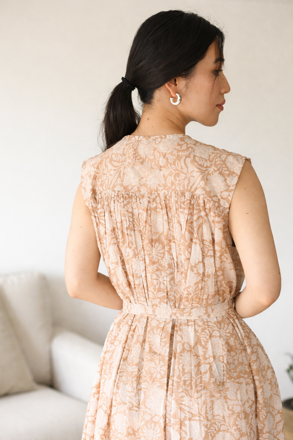 Woman wearing a beige floral dress with a neutral background