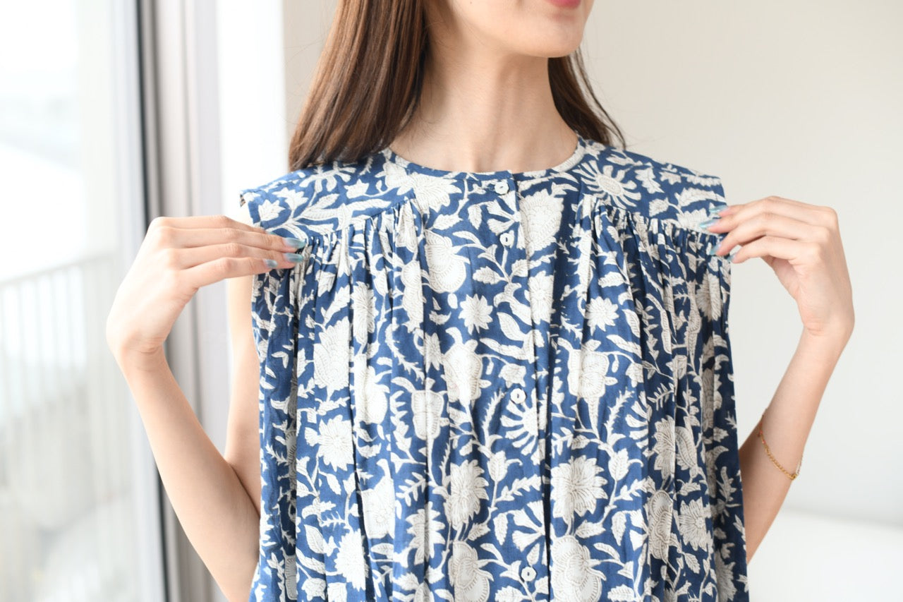 Woman holding up a blue and white floral dress against a neutral background