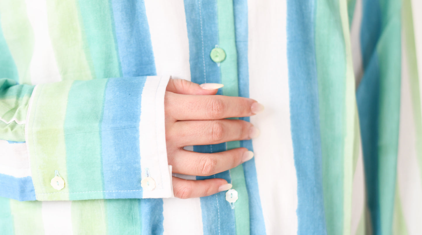 Close-up of a person wearing a pastel striped shirt with a blurred background