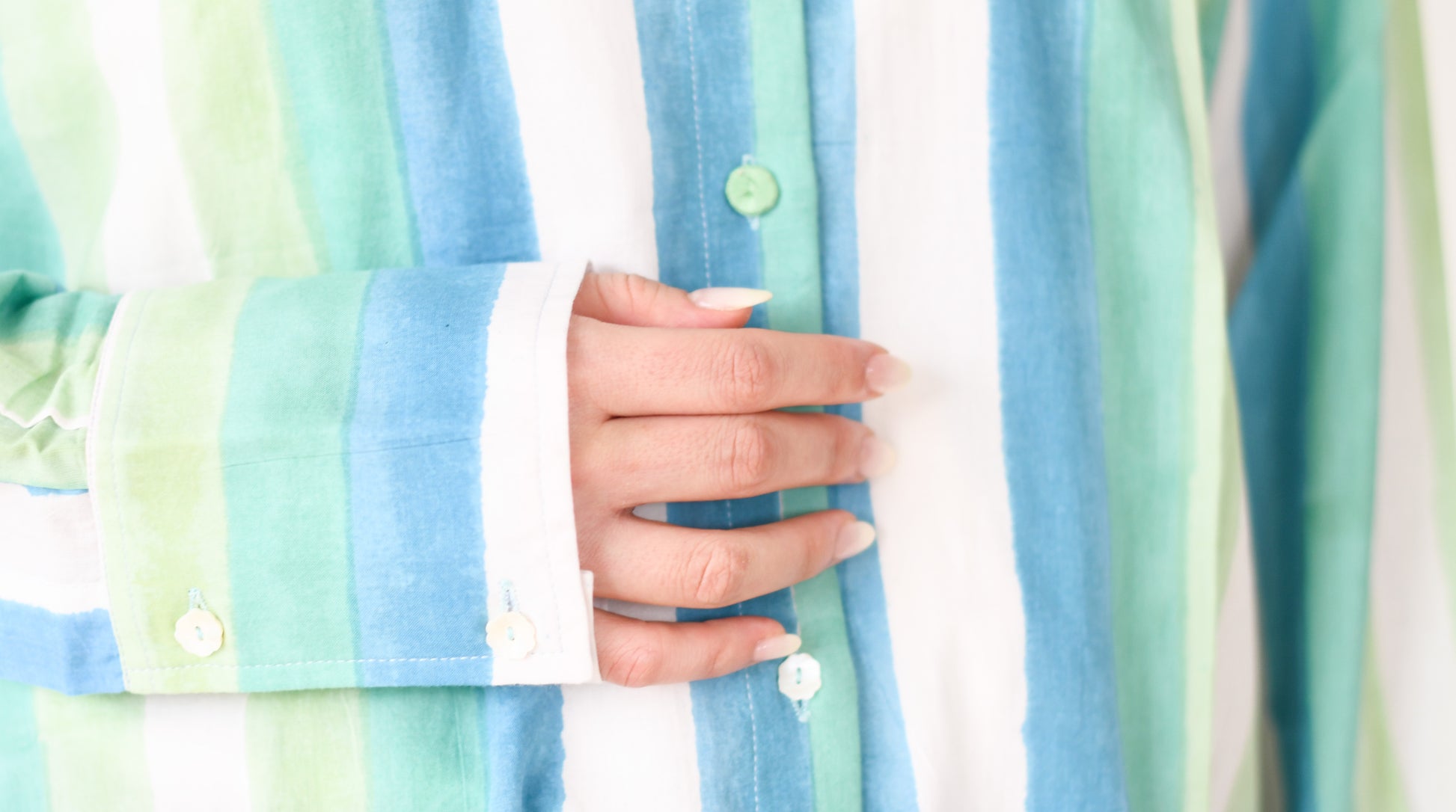 Close-up of a person wearing a pastel striped shirt with a blurred background