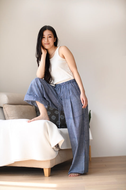 Woman wearing a white top and blue checkered pants.
