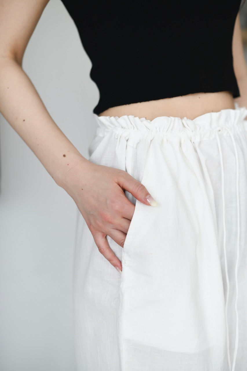 Person wearing a black top and white pants on a plain background