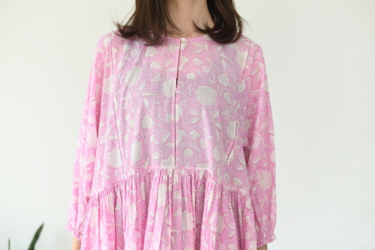 Person wearing a pink floral dress against a white background
