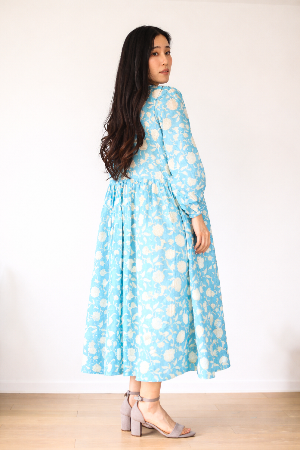 Woman wearing a blue floral dress against a white background