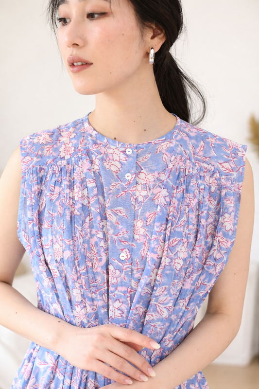 Woman wearing a blue and pink floral dress against a plain background