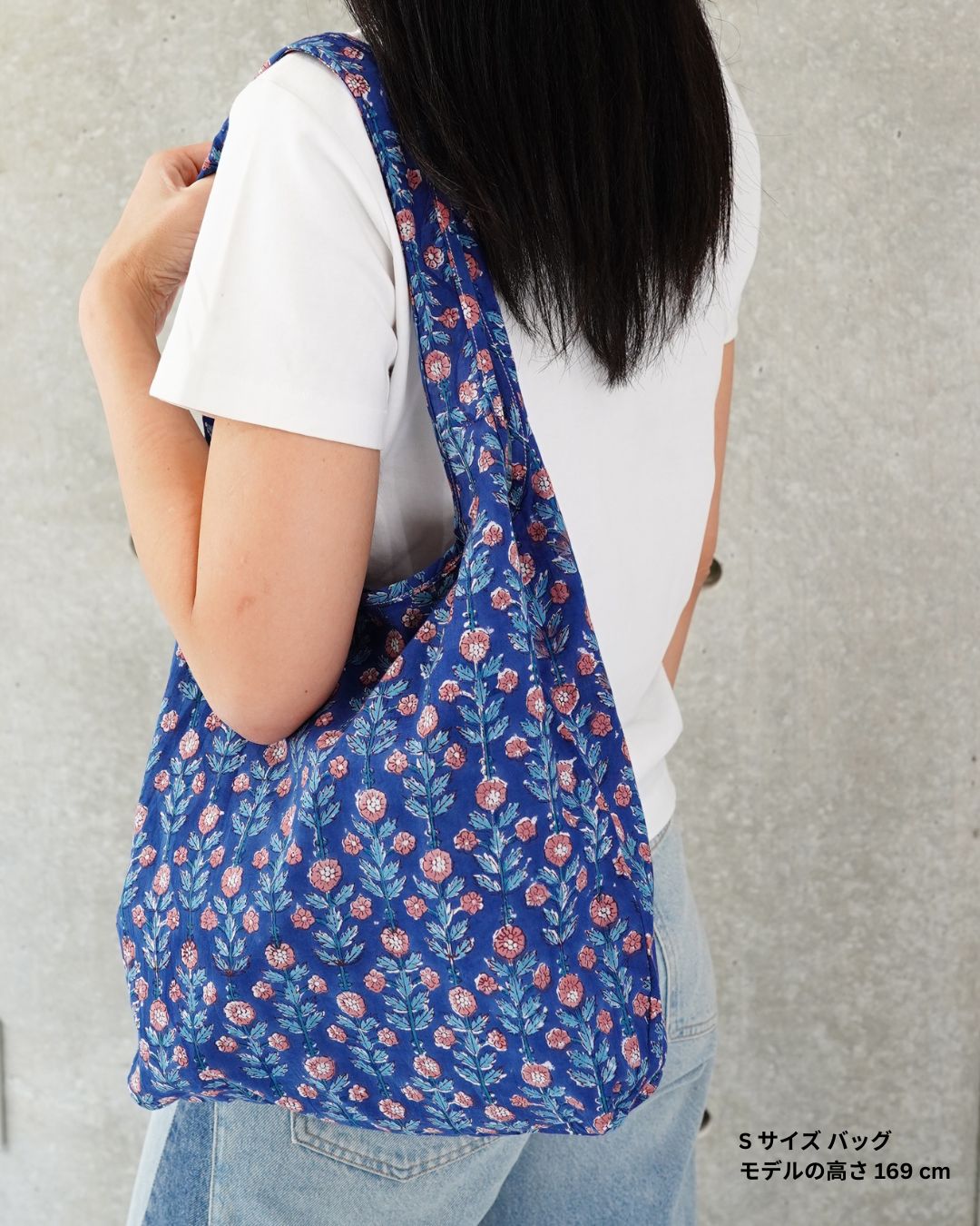 Person wearing a blue floral-patterned bag against a plain background