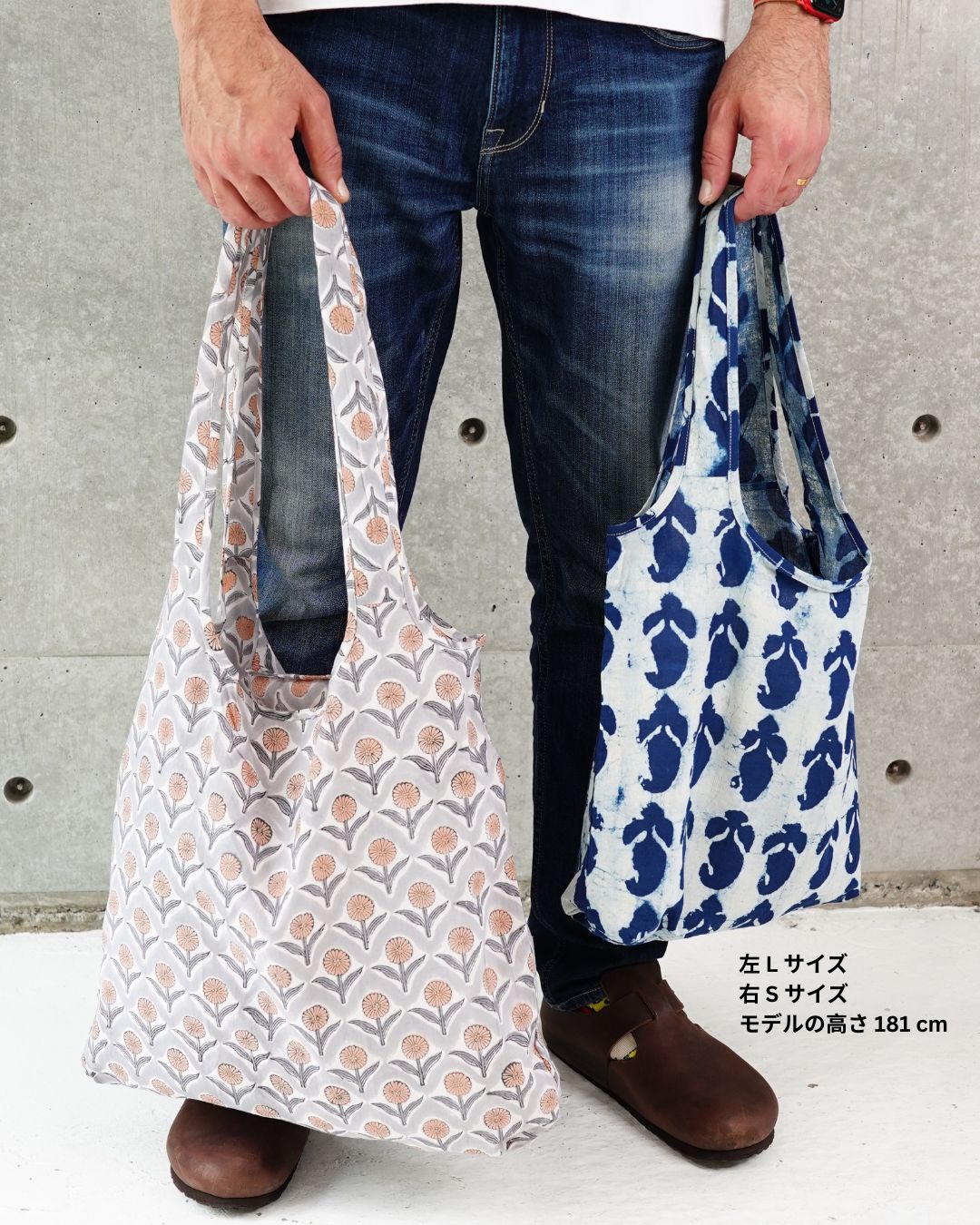 Person holding two patterned cotton eco bags against a concrete wall.