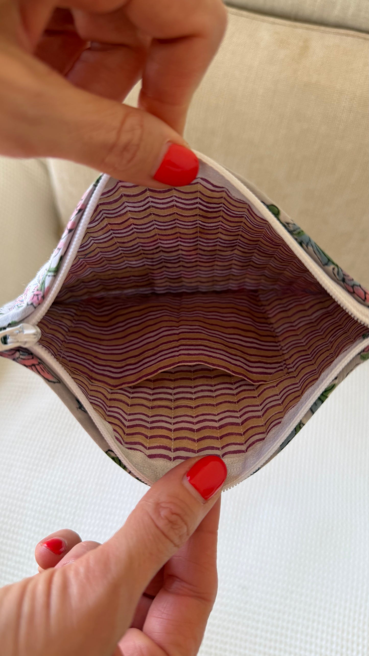 Close-up of a hand holding an open fabric pouch with a striped interior.