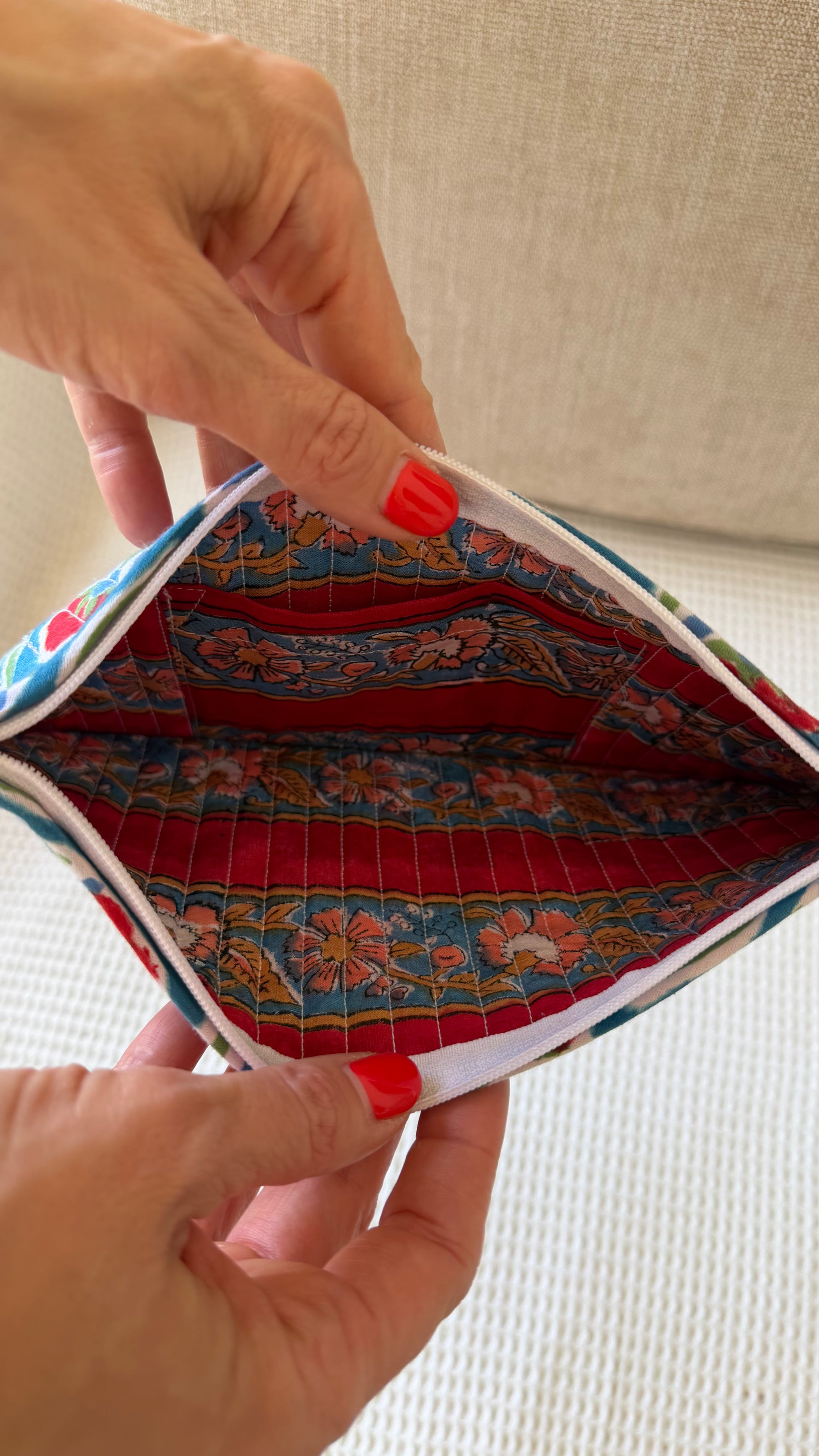 Hand holding a colorful fabric pouch with floral patterns.