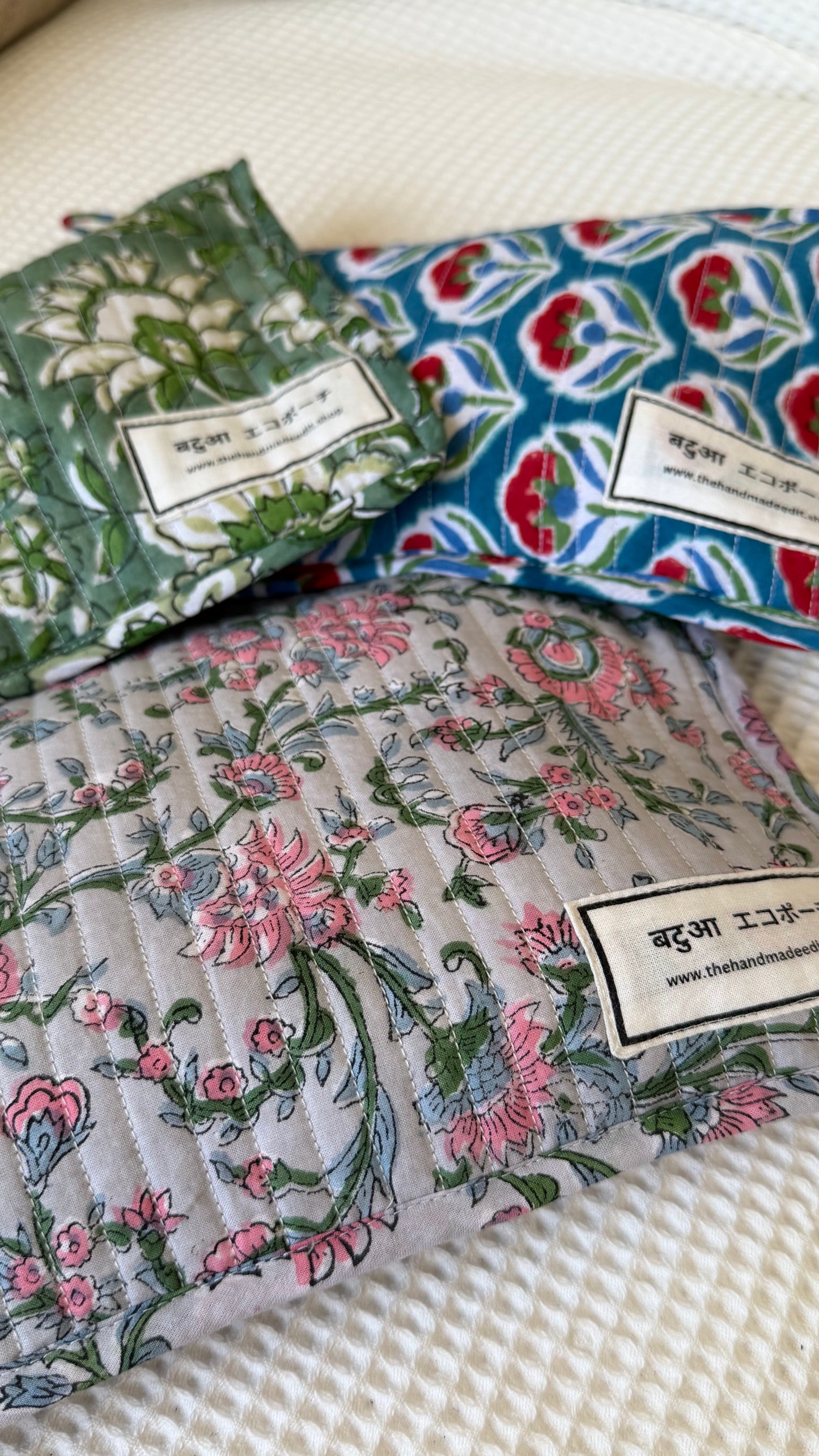 Three patterned fabric pouches  with labels on a textured surface