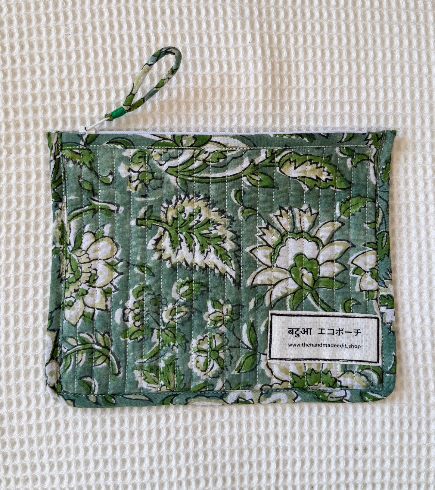 Green floral fabric pouch on a textured beige background