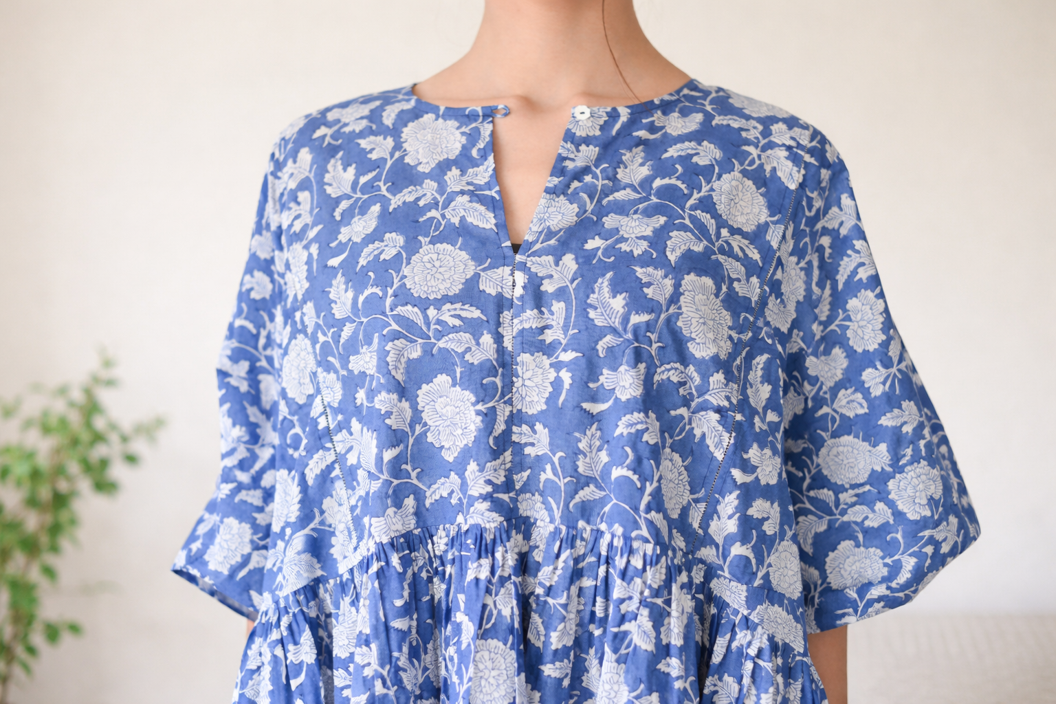 Blue floral dress worn by a person on a plain background