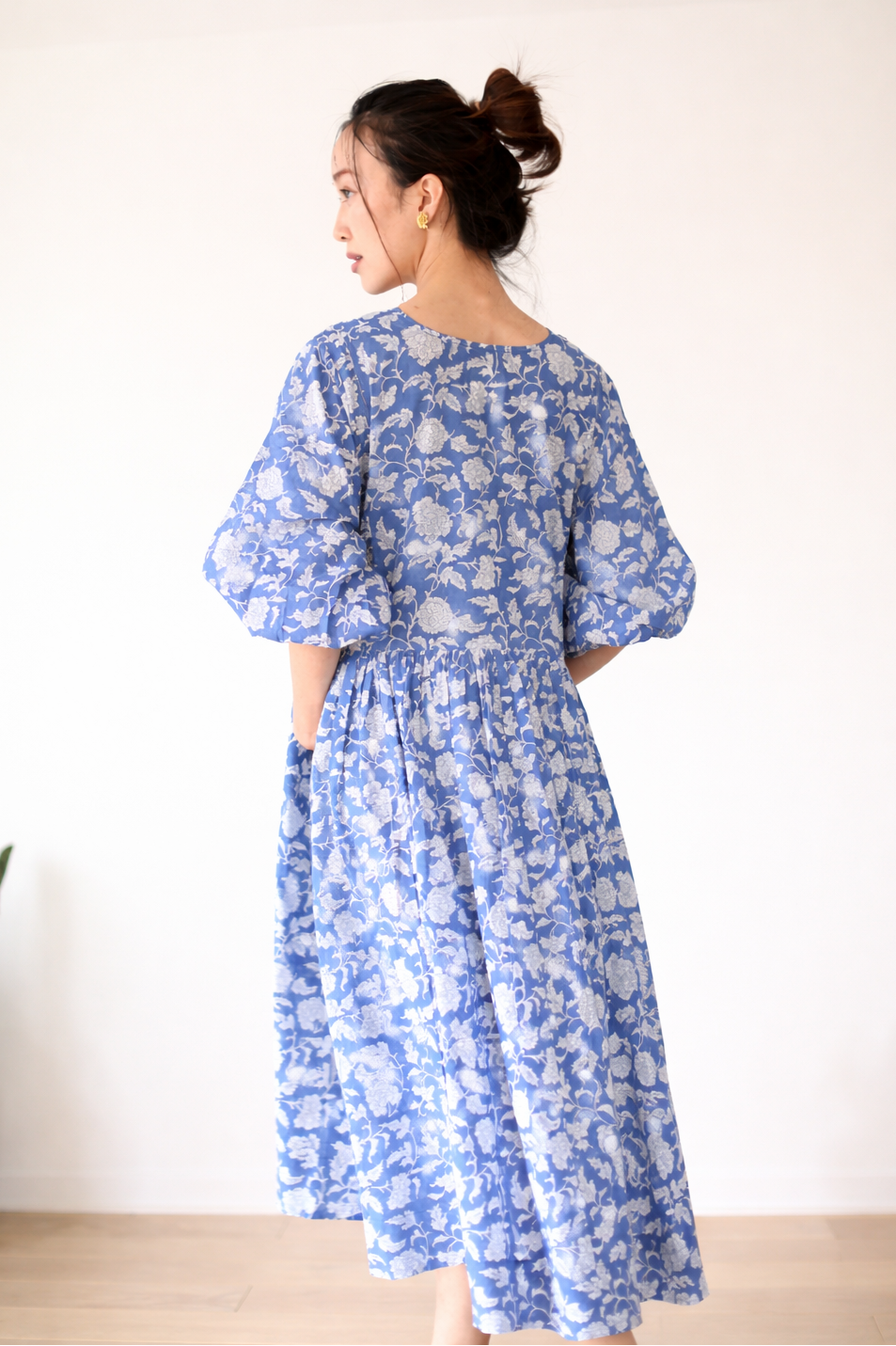 Woman wearing a blue floral dress against a white background