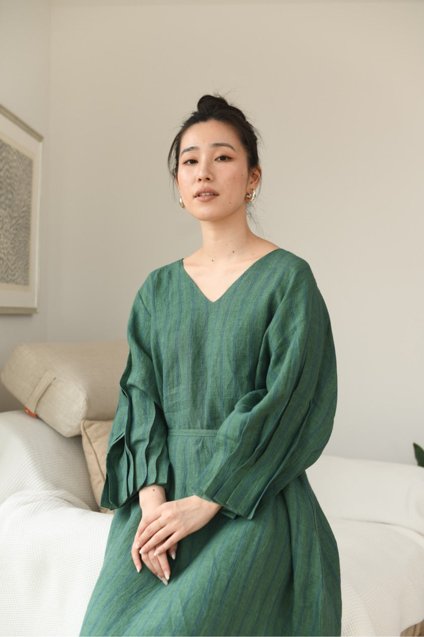 Woman in a green linen dress standing in a living room.