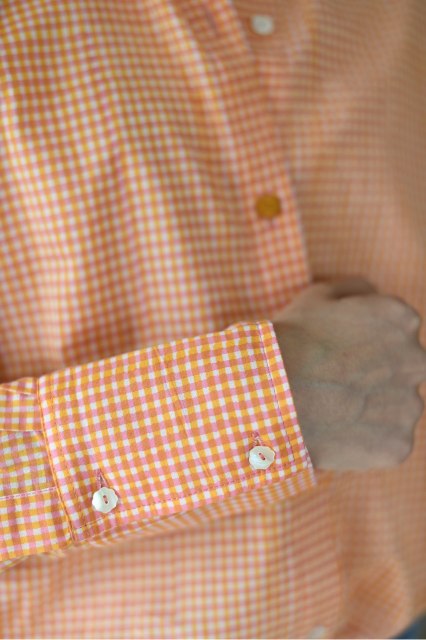 Close-up of a checkered shirt with orange and white pattern.