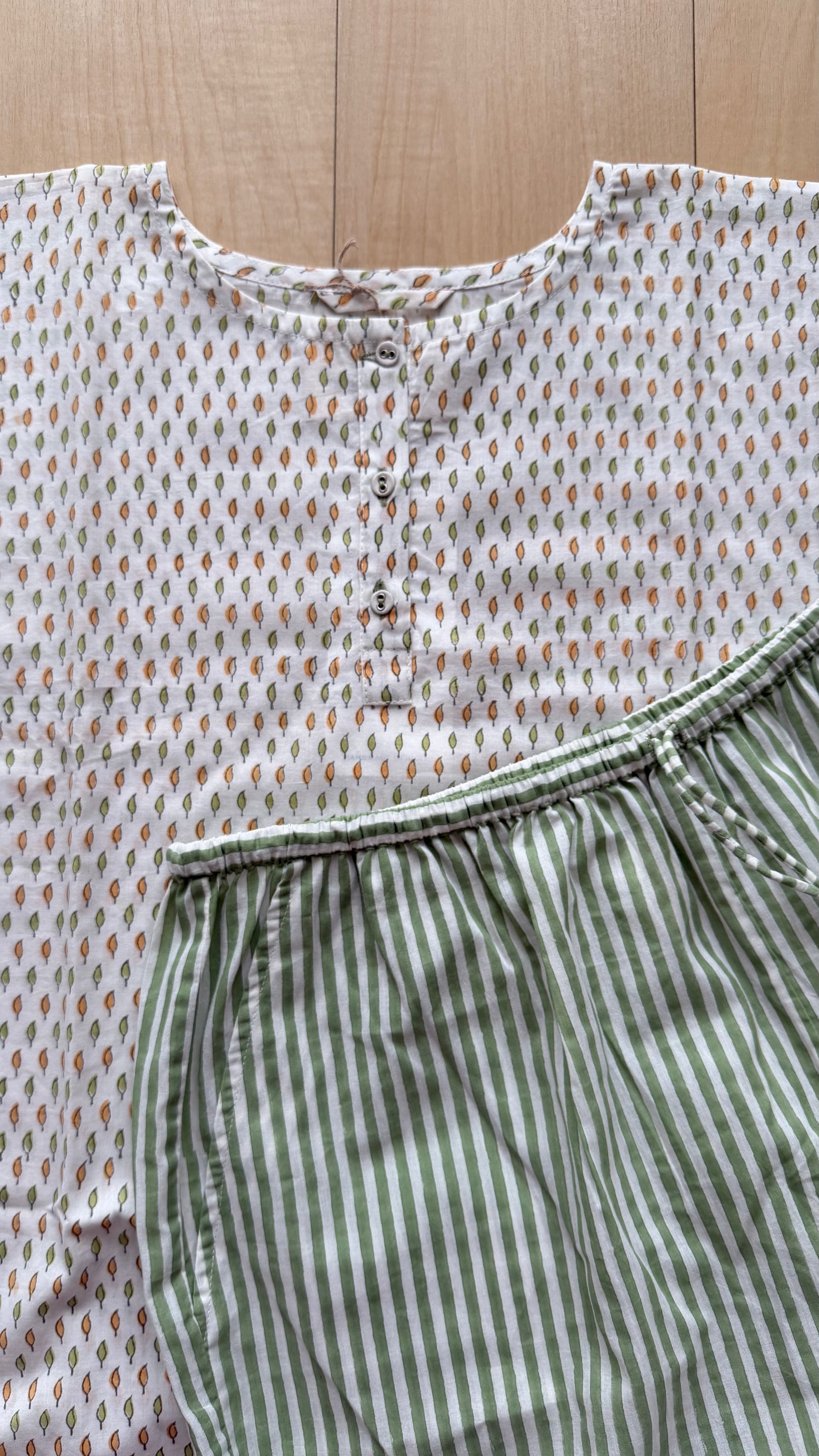 Top with a patterned design and green striped pants on a wooden surface